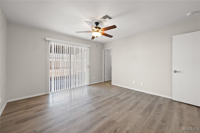 unfurnished room with visible vents, ceiling fan, baseboards, and wood finished floors