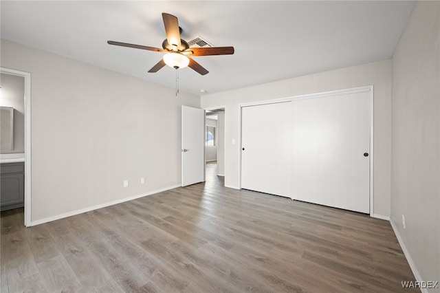 unfurnished bedroom with a closet, baseboards, connected bathroom, and light wood finished floors