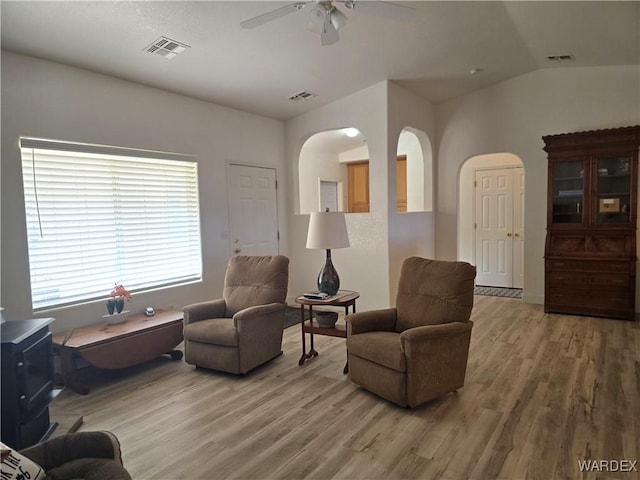 living area with vaulted ceiling, light wood-style floors, visible vents, and ceiling fan