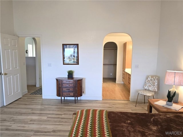 interior space featuring baseboards, arched walkways, and light wood finished floors