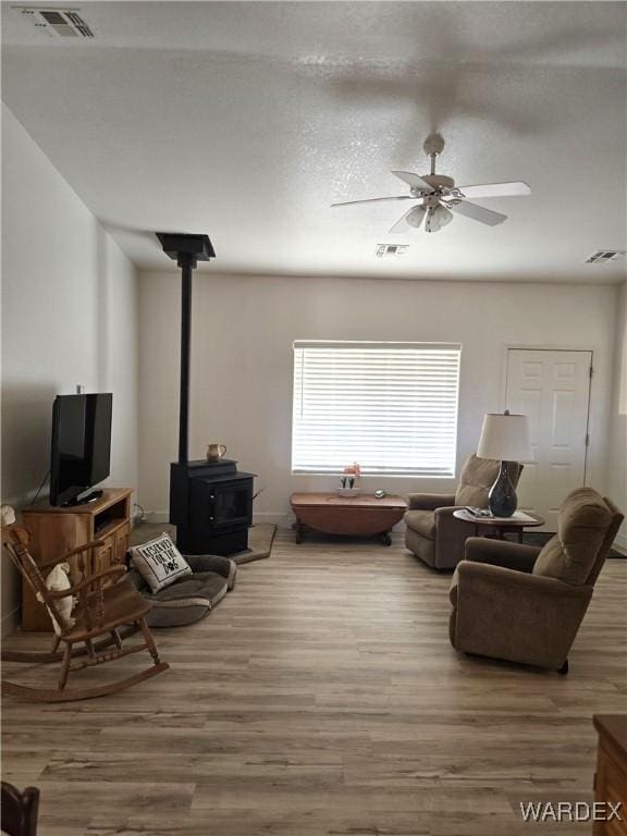 living room featuring ceiling fan, visible vents, and wood finished floors