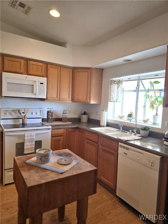 kitchen featuring white appliances, dark countertops, light wood-style floors, and visible vents