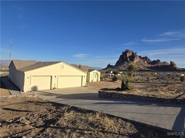 exterior space with stucco siding, a mountain view, concrete driveway, and a garage