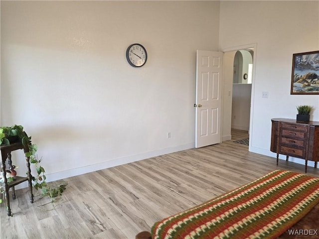 unfurnished bedroom featuring baseboards, arched walkways, and wood finished floors