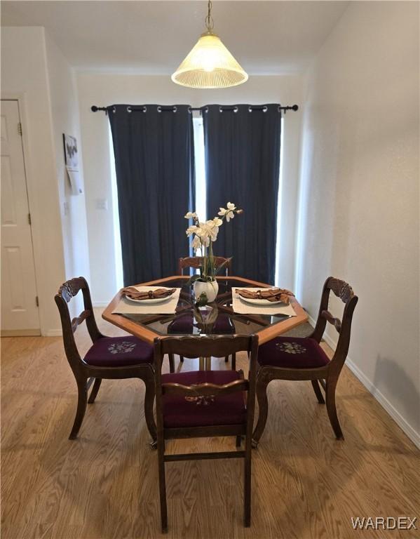 dining area featuring light wood finished floors and baseboards