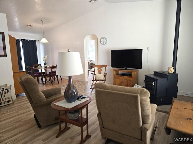 living room featuring vaulted ceiling, wood finished floors, arched walkways, and visible vents