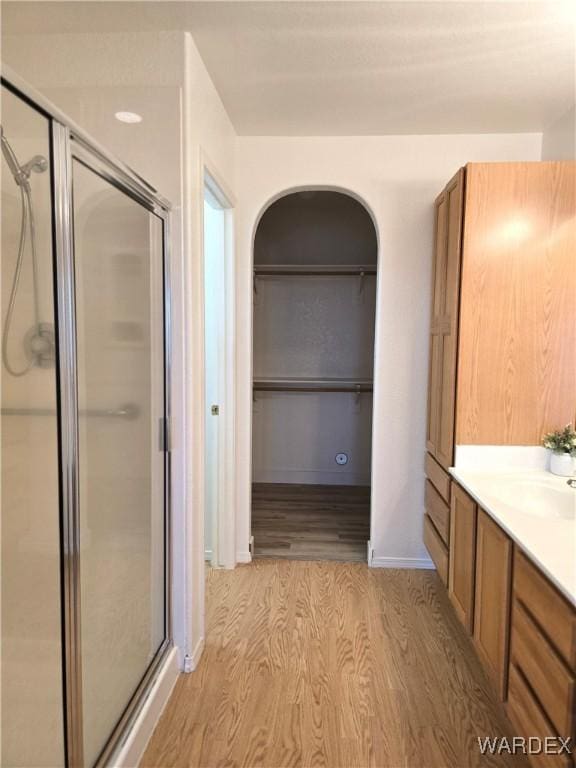 bathroom with a stall shower, vanity, baseboards, and wood finished floors