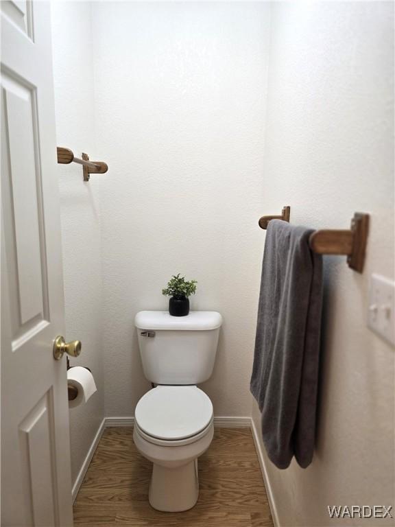 bathroom featuring toilet, wood finished floors, and baseboards