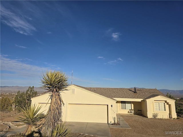 view of front facade with stucco siding, a mountain view, concrete driveway, and an attached garage