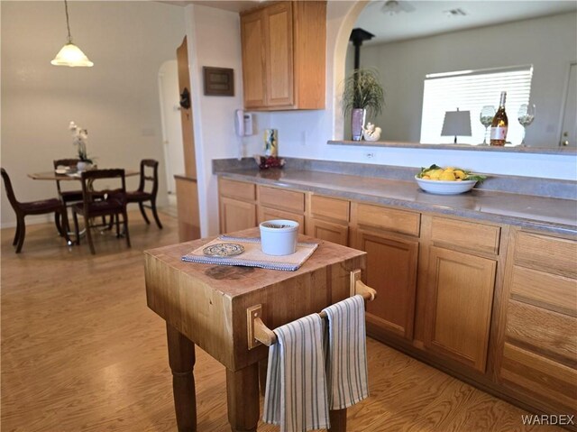 kitchen featuring dark countertops, light wood finished floors, arched walkways, and decorative light fixtures