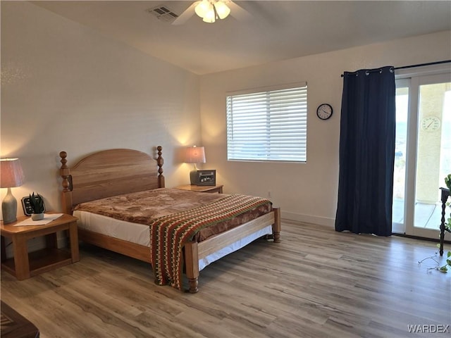 bedroom with visible vents, multiple windows, wood finished floors, and access to outside