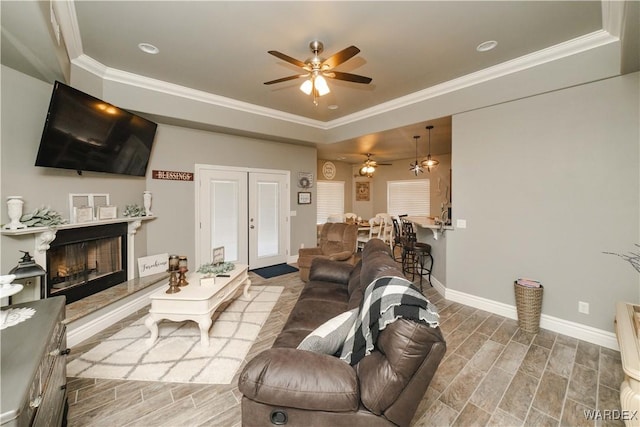 living area with wood finish floors, french doors, crown molding, a high end fireplace, and baseboards