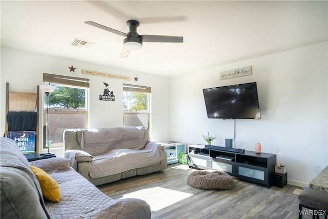 living room with ceiling fan, wood finished floors, visible vents, and baseboards