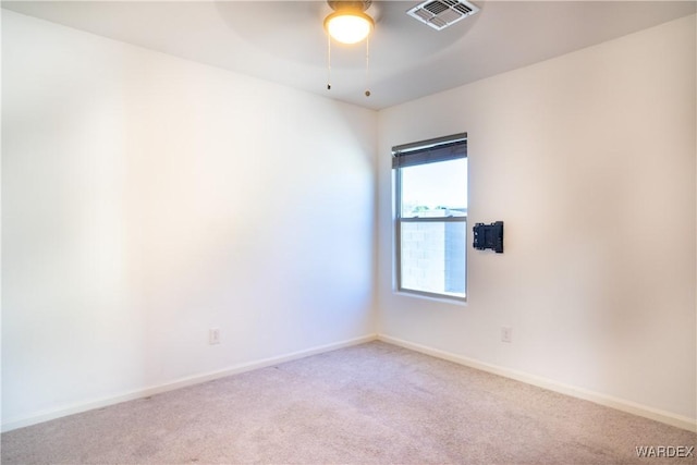 unfurnished room with a ceiling fan, visible vents, light carpet, and baseboards