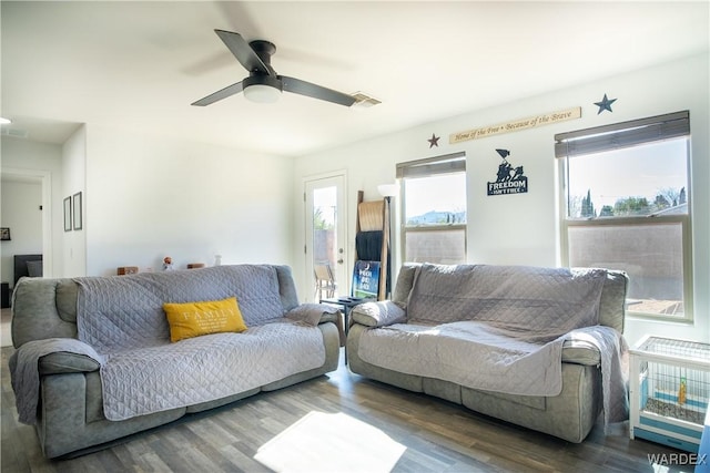 living area featuring visible vents, dark wood finished floors, and a ceiling fan