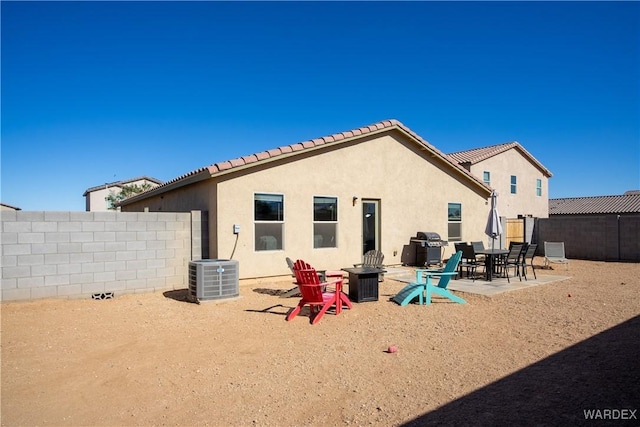 rear view of house featuring a fire pit, a patio, fence, cooling unit, and stucco siding