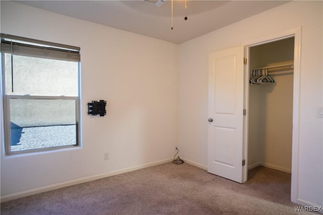 unfurnished bedroom with light carpet, baseboards, a walk in closet, and a closet