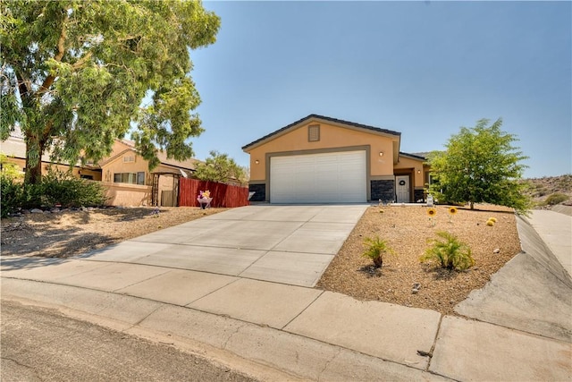 3492 Tres Alamos Dr, Bullhead City, AZ 86442 - view of front of home featuring stucco siding, driveway, stone siding, and an attached garage
