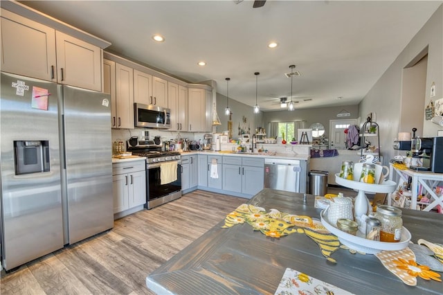 3492 Tres Alamos Dr, Bullhead City, AZ 86442 - kitchen with appliances with stainless steel finishes, a ceiling fan, light wood-style floors, a peninsula, and light countertops