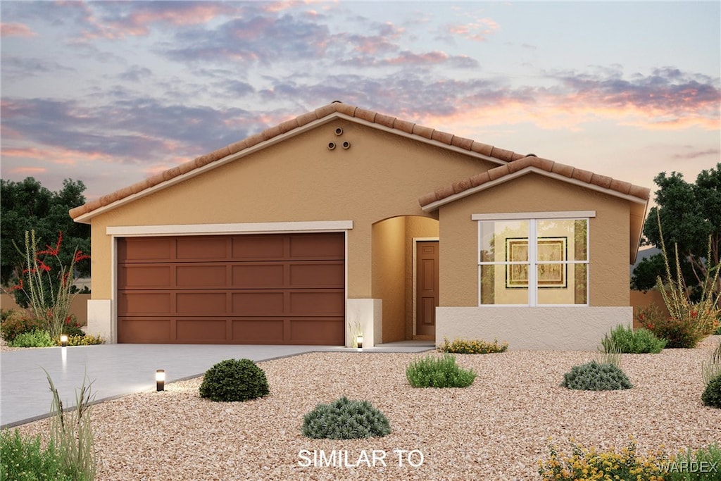 view of front facade featuring a garage, concrete driveway, a tile roof, and stucco siding