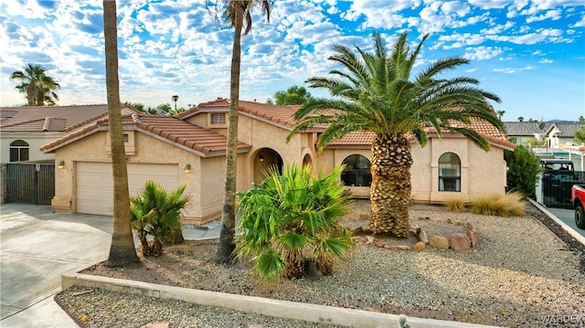 mediterranean / spanish house featuring a garage, driveway, a tiled roof, and stucco siding