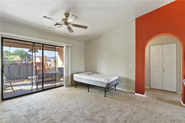 bedroom featuring light carpet, arched walkways, baseboards, a ceiling fan, and access to outside