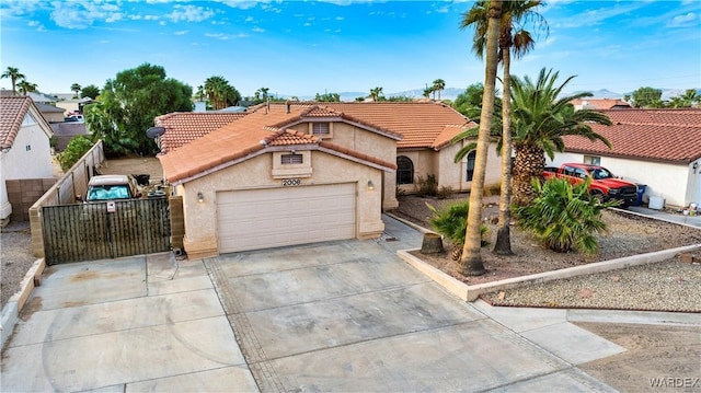 mediterranean / spanish house with driveway, a garage, a tiled roof, fence, and stucco siding