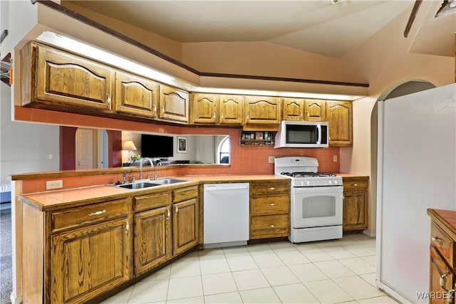 kitchen featuring white appliances, brown cabinets, and a sink