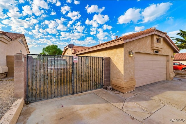 exterior space with an outdoor structure, a tile roof, a gate, and stucco siding