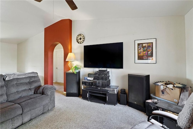 carpeted living area featuring arched walkways, vaulted ceiling, and a ceiling fan