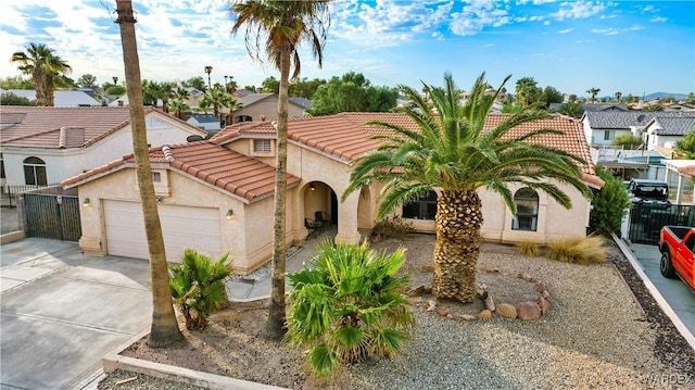 mediterranean / spanish-style home featuring an attached garage, a tile roof, a residential view, and stucco siding