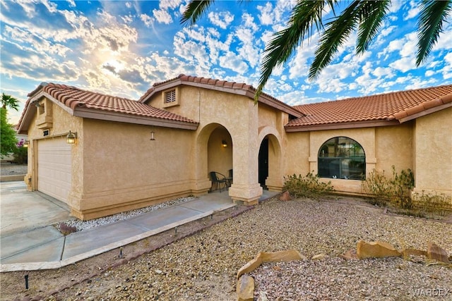 mediterranean / spanish house with an attached garage, driveway, and stucco siding