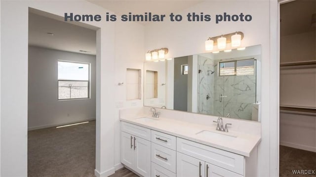 full bathroom with a sink, a marble finish shower, baseboards, and double vanity