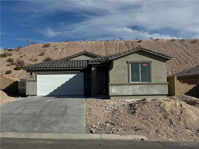 single story home with stucco siding, a tile roof, fence, concrete driveway, and a garage