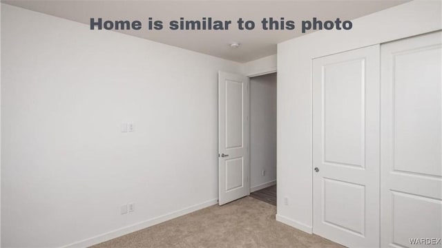 unfurnished bedroom featuring light colored carpet, a closet, and baseboards