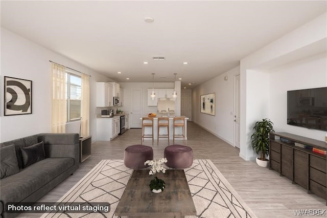 living room featuring recessed lighting, visible vents, and light wood-style flooring