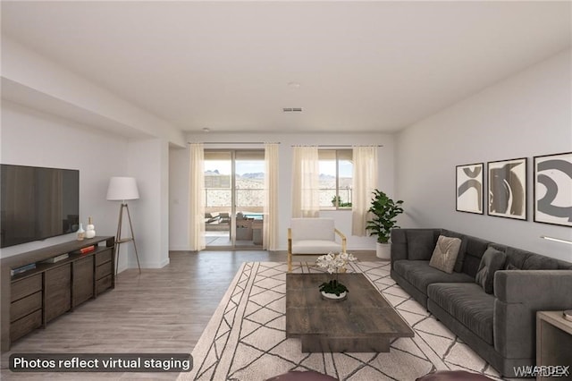 living room with light wood-style flooring, baseboards, and visible vents