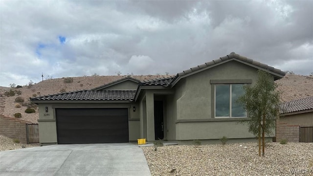 view of front of house featuring fence, driveway, an attached garage, stucco siding, and a tile roof