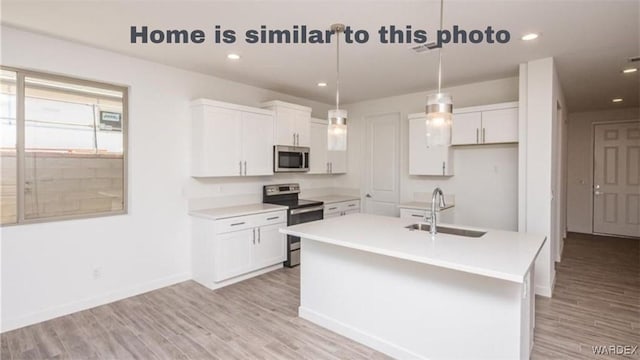 kitchen with a sink, light wood-style floors, appliances with stainless steel finishes, and white cabinets