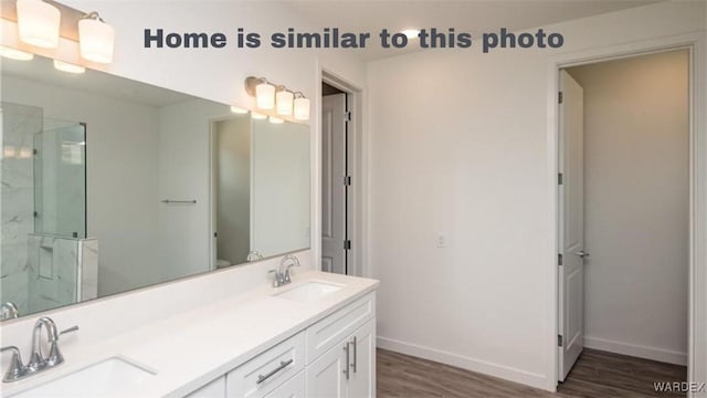 full bathroom featuring a marble finish shower, wood finished floors, baseboards, and a sink