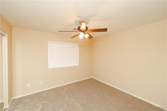 empty room with a ceiling fan, carpet flooring, and baseboards