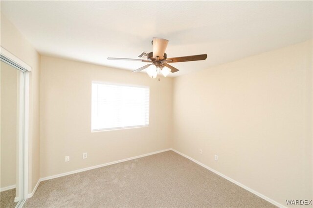 carpeted empty room featuring ceiling fan and baseboards