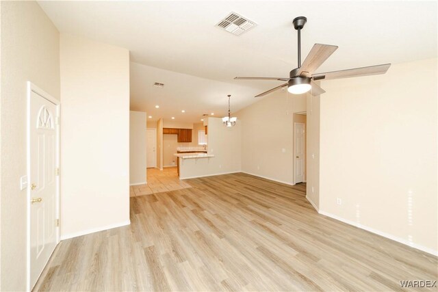 unfurnished living room with lofted ceiling, light wood-style flooring, ceiling fan with notable chandelier, visible vents, and baseboards