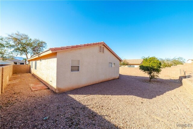 view of side of home with a fenced backyard and stucco siding