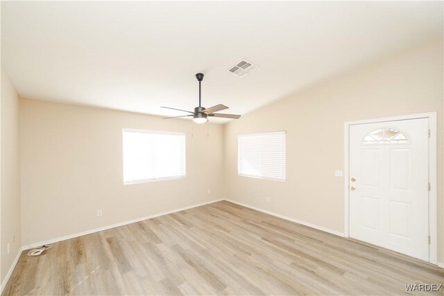 spare room with ceiling fan, visible vents, baseboards, vaulted ceiling, and light wood finished floors