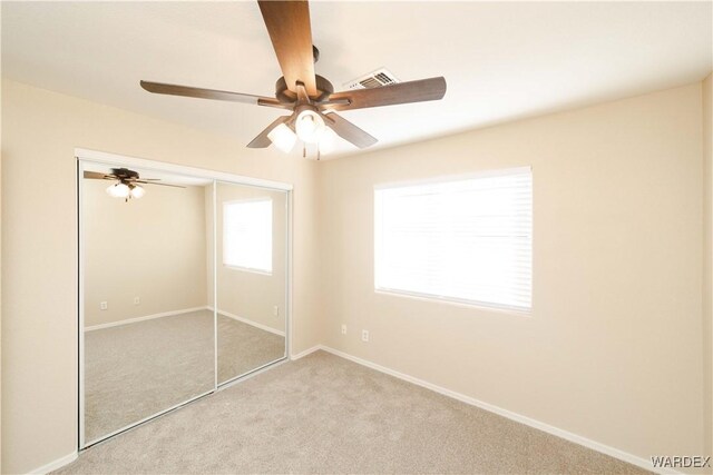 unfurnished bedroom with light colored carpet, a ceiling fan, baseboards, visible vents, and a closet