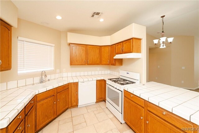 kitchen with tile countertops, white appliances, a sink, visible vents, and pendant lighting