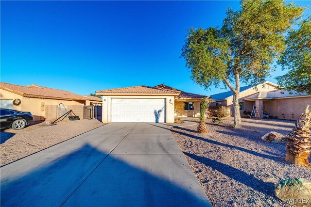 view of front facade with concrete driveway, an attached garage, a tiled roof, and stucco siding