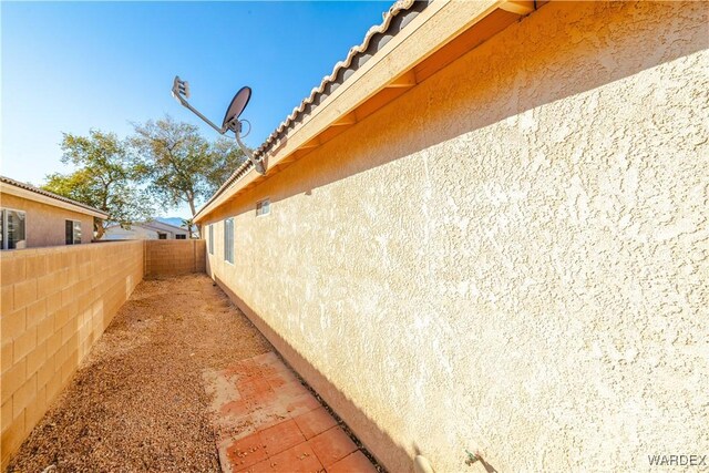 view of home's exterior featuring a tile roof, fence, and stucco siding