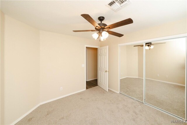 unfurnished bedroom featuring ceiling fan, light carpet, visible vents, baseboards, and a closet